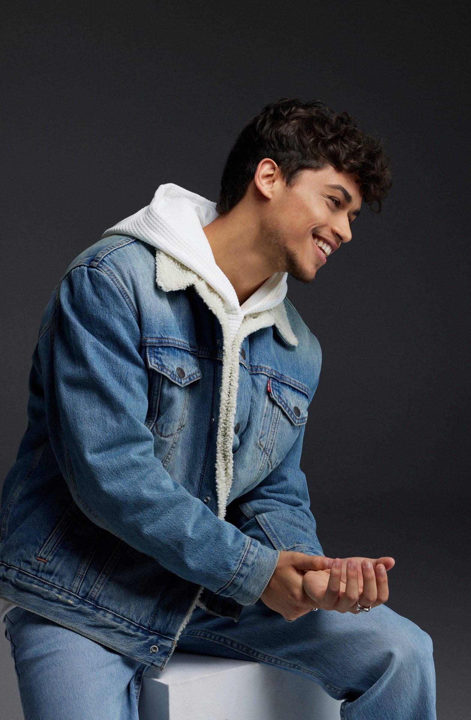 Harris J laughing in a denim jacket and white hoodie