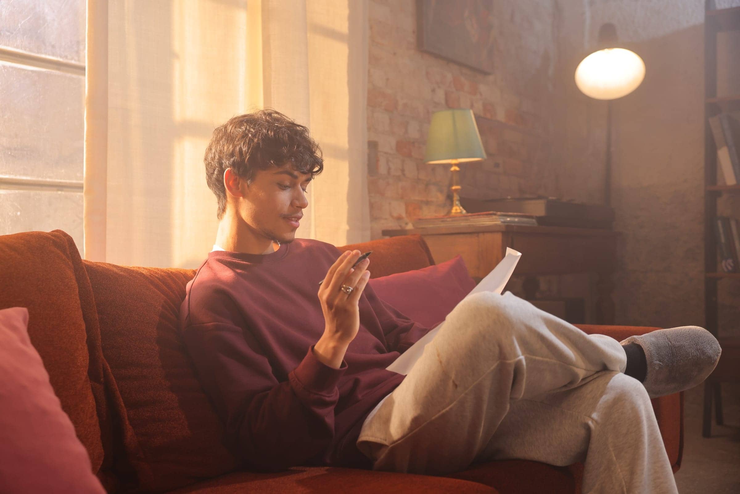 Harris J writing lyrics on a sofa in warm afternoon light